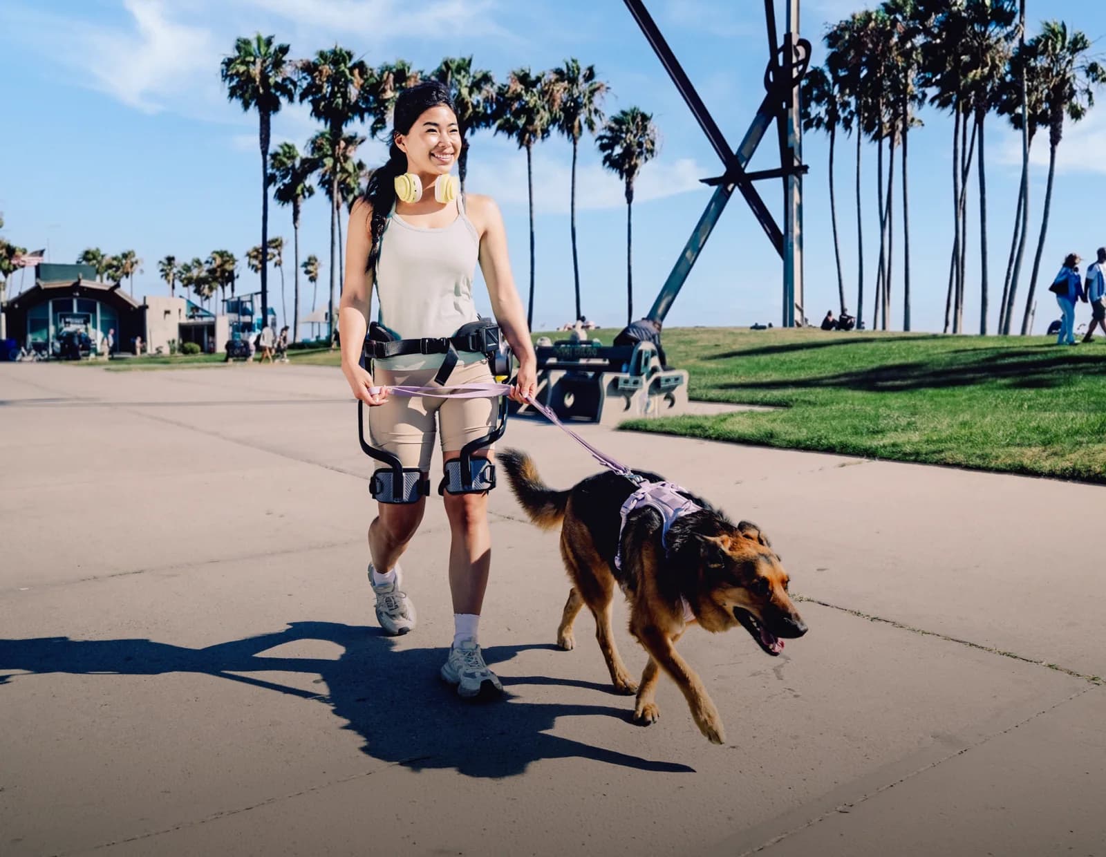 A woman wearing an Ascentiz H Pro walks a dog along a paved path.