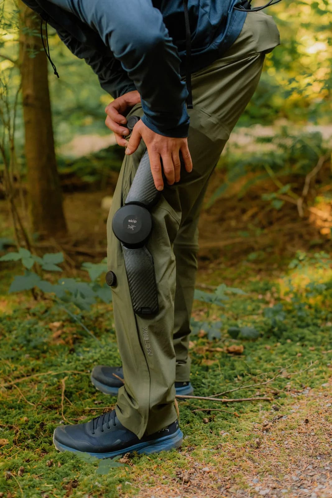 A close view of MO/GO pants and knee hardware worn over hiking shoes.